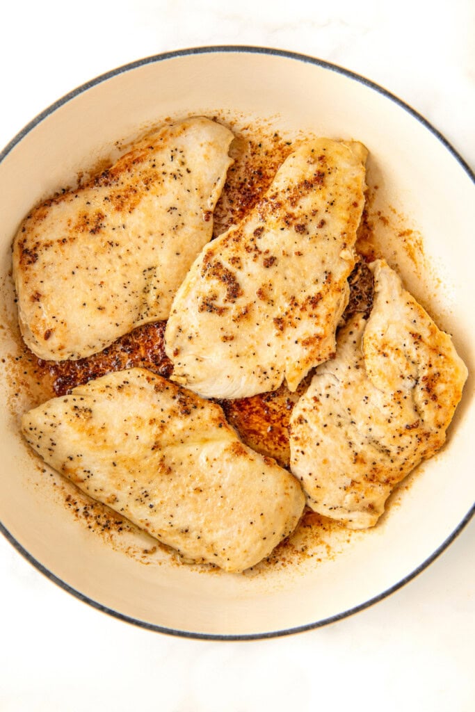 Cooked, golden brown, thin chicken breasts in a skillet.