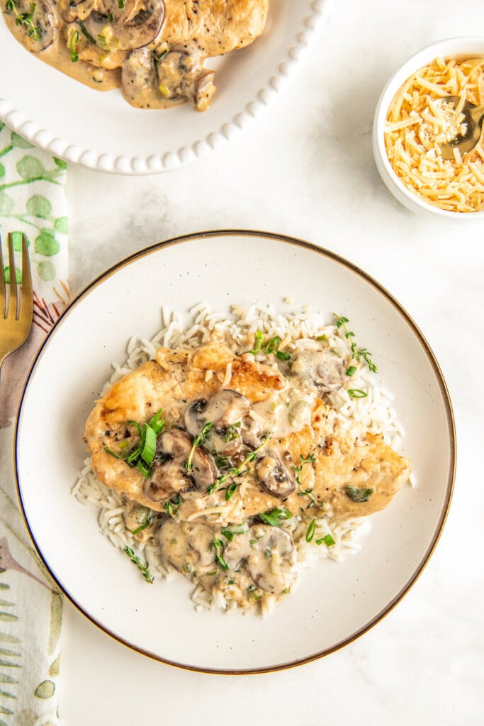 Plate of asiago chicken with garlic-thyme cream and mushrooms, served with rice.