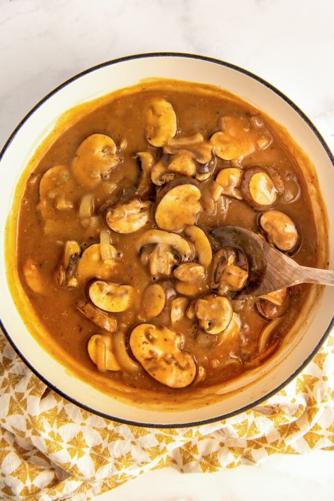 Mushrooms cooking in a rich brown gravy.