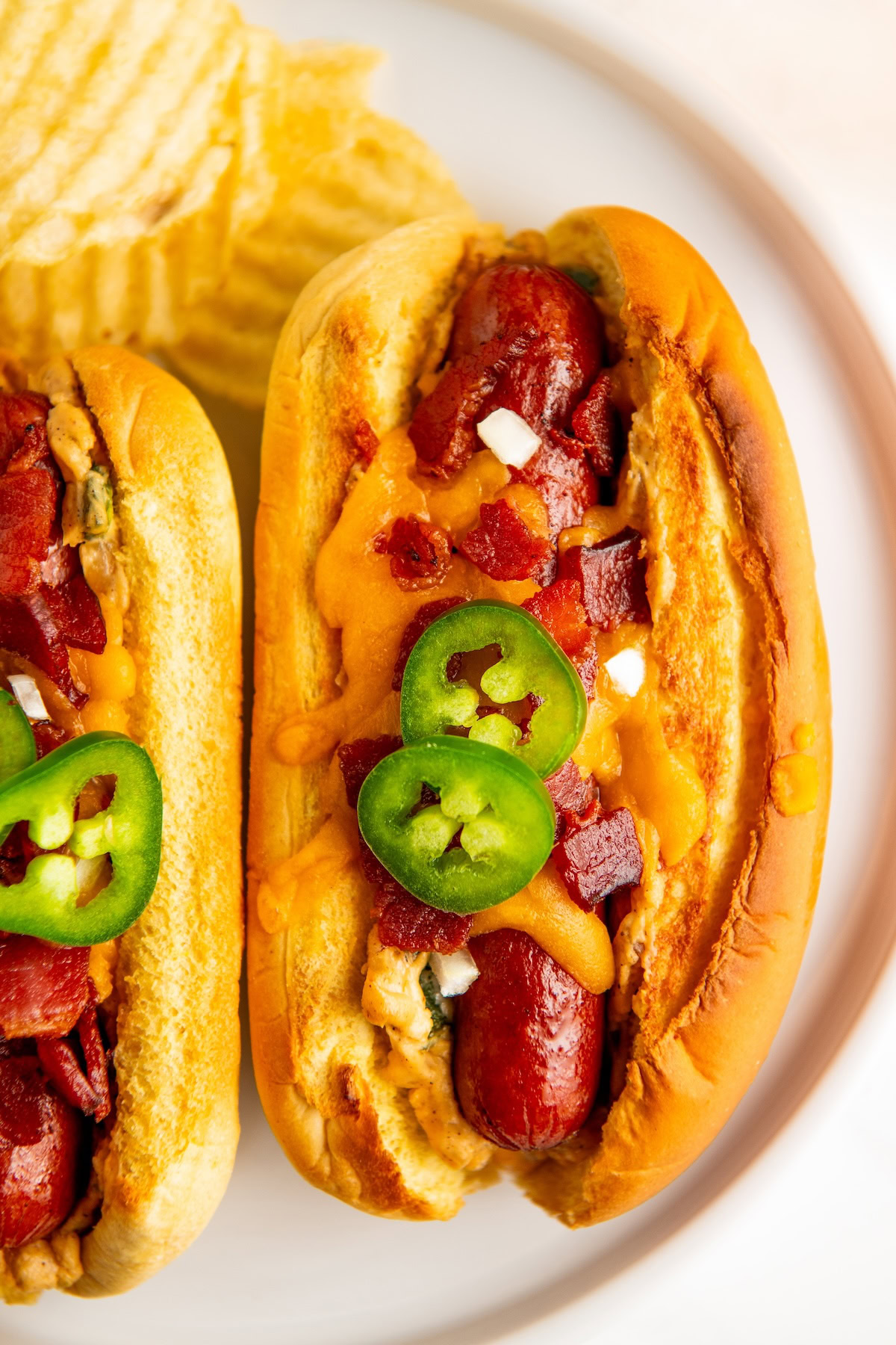 Jalapeño Popper Hot Dogs stuffed with a creamy jalapeño filling topped with lots of cheddar cheese and a crispy bacon in a toasted bun.