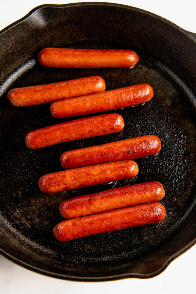 Cooking the sausages on the skillet. 