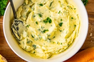 Bowl of garlic butter spread with fresh parsley on top.