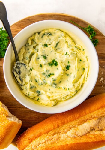 Bowl of garlic butter spread with fresh parsley on top.