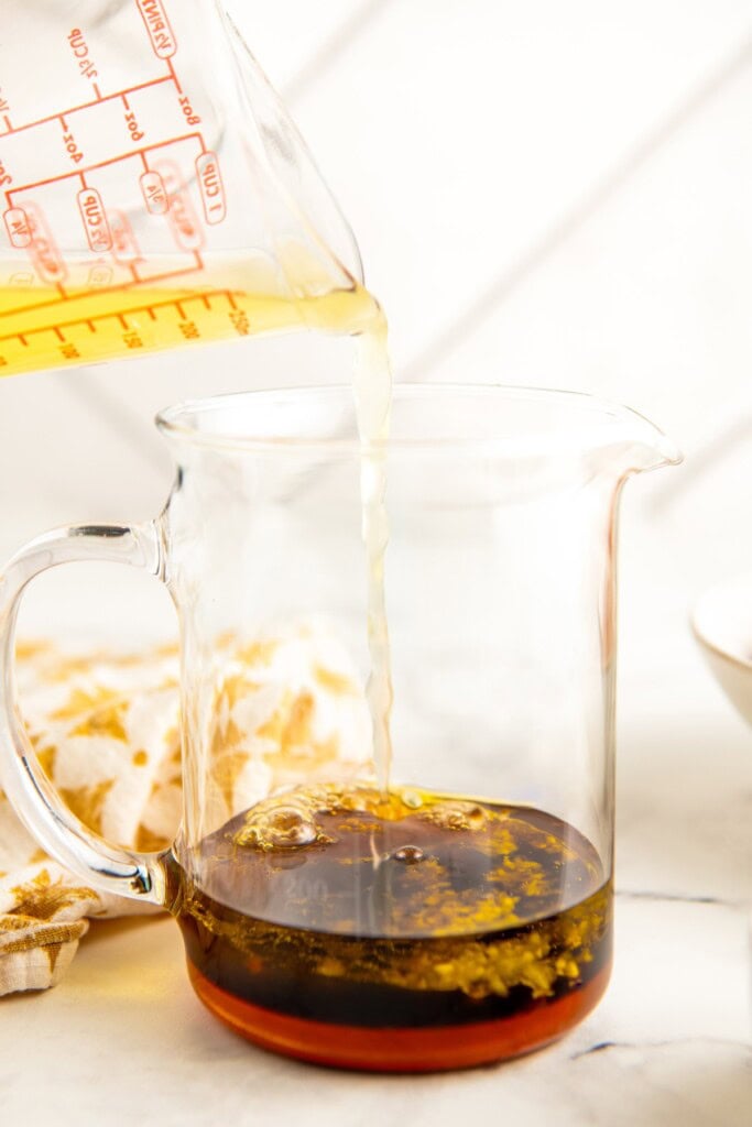 Oil is being poured into a jar with other marinade ingredients. 