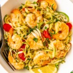 Bowl of lemon garlic shrimp zoodles with parmesan, parsley, and juicy tomatoes.