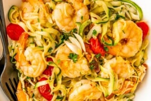 Bowl of lemon garlic shrimp zoodles with parmesan, parsley, and juicy tomatoes.