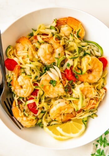 Bowl of lemon garlic shrimp zoodles with parmesan, parsley, and juicy tomatoes.