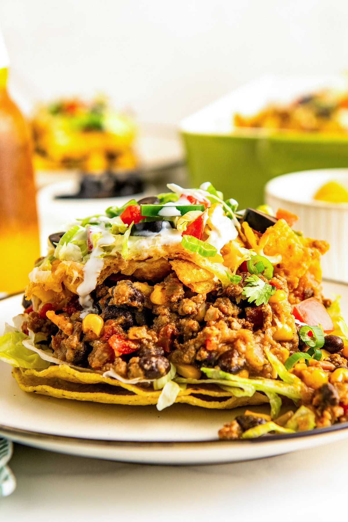 A serving of taco casserole with fritos on top of two crispy tortilla shells on a plate.