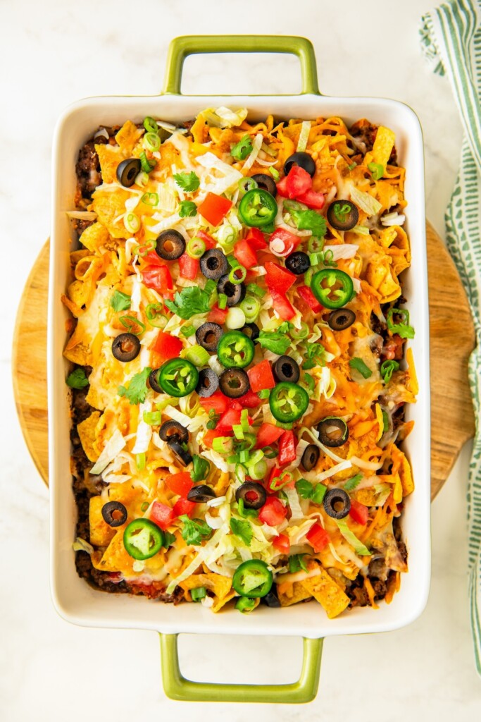 Freshly baked casserole topped with shredded lettuce, cilantro, tomatoes, jalapeños, green onions and sliced olives.