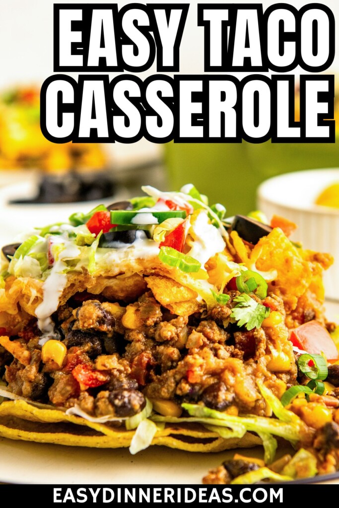 A plate of ground beef taco casserole with fritos and sour cream drizzled on top.