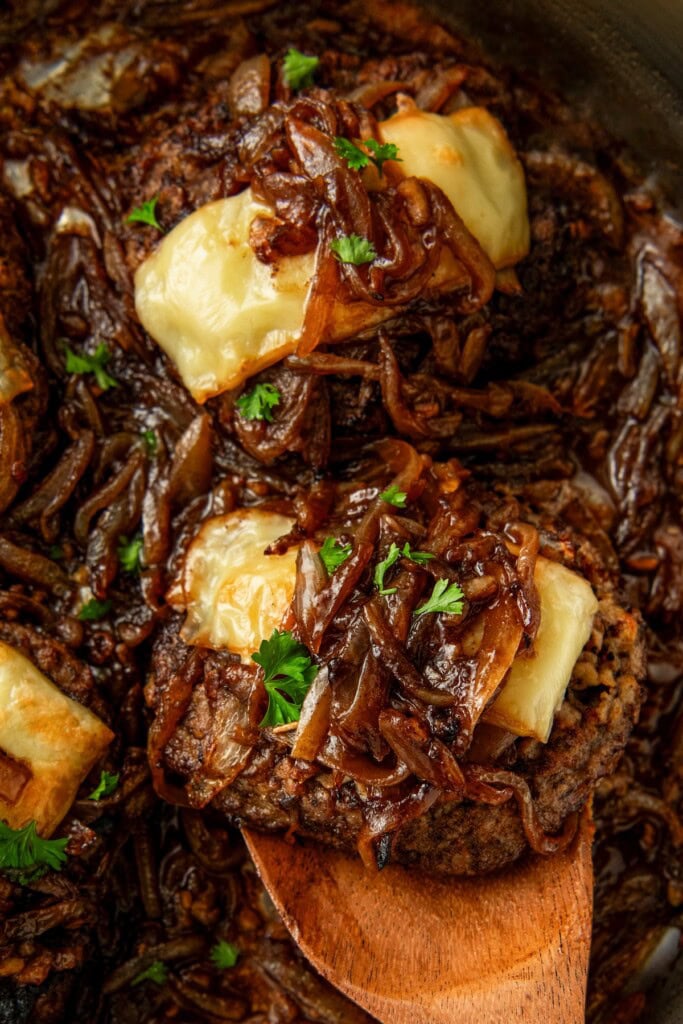 Cube steak and gravy is garnished with fresh herbs.