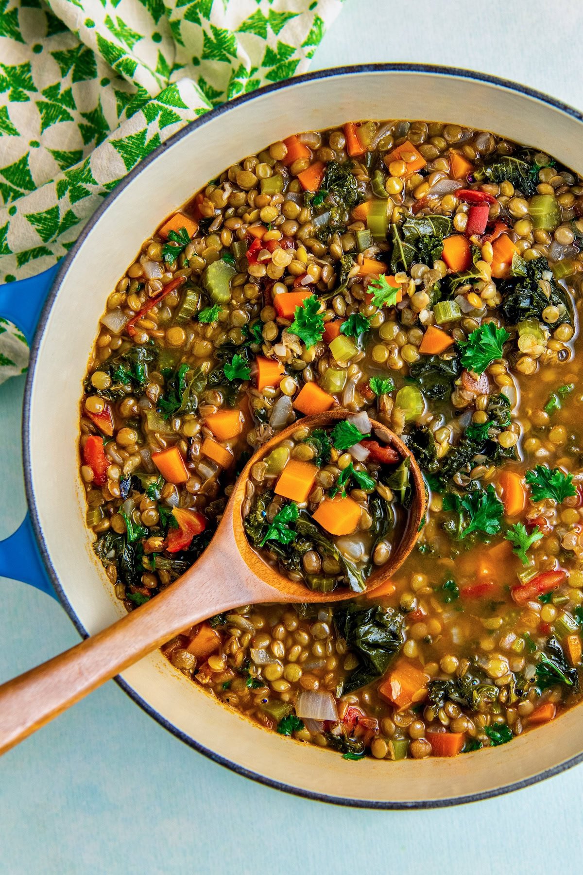 Cooked easy lentil soup with vegetables in the pot with a wooden spoon ready to serve.