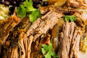 Tender bites of shredded mojo pork are plated with rice and beans.