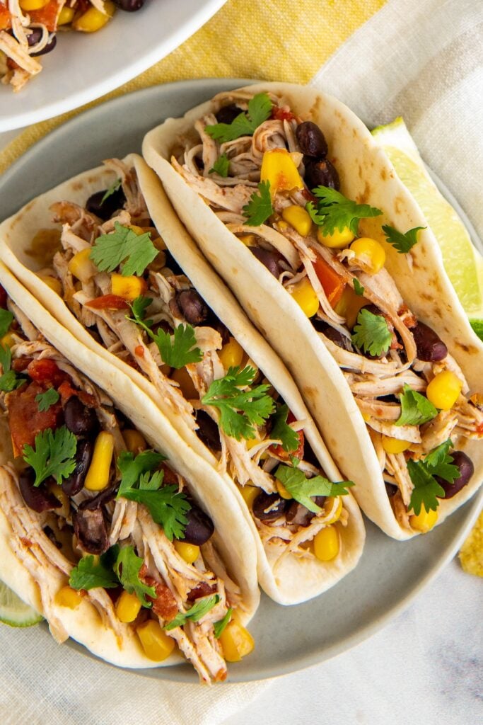 Slow cooker Mexican chicken served in warm flour tortillas with cilantro on top.