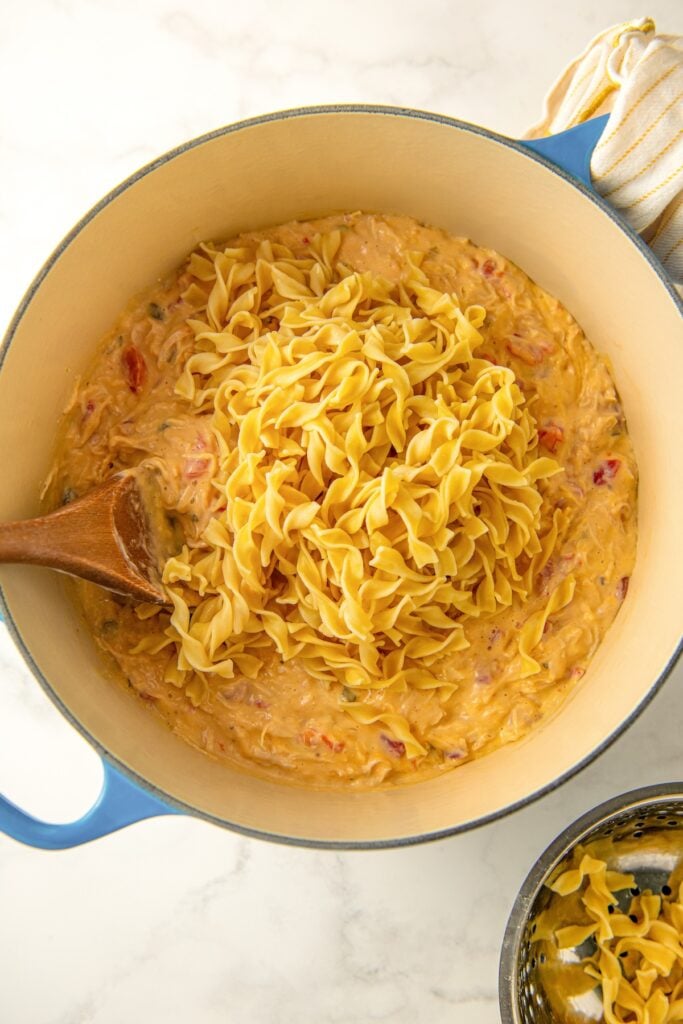 Cooked egg noodles are being mixed in a large pot.