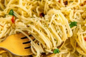 Angel hair pasta is topped with butter, garlic, herbs, and crushed red pepper flakes.