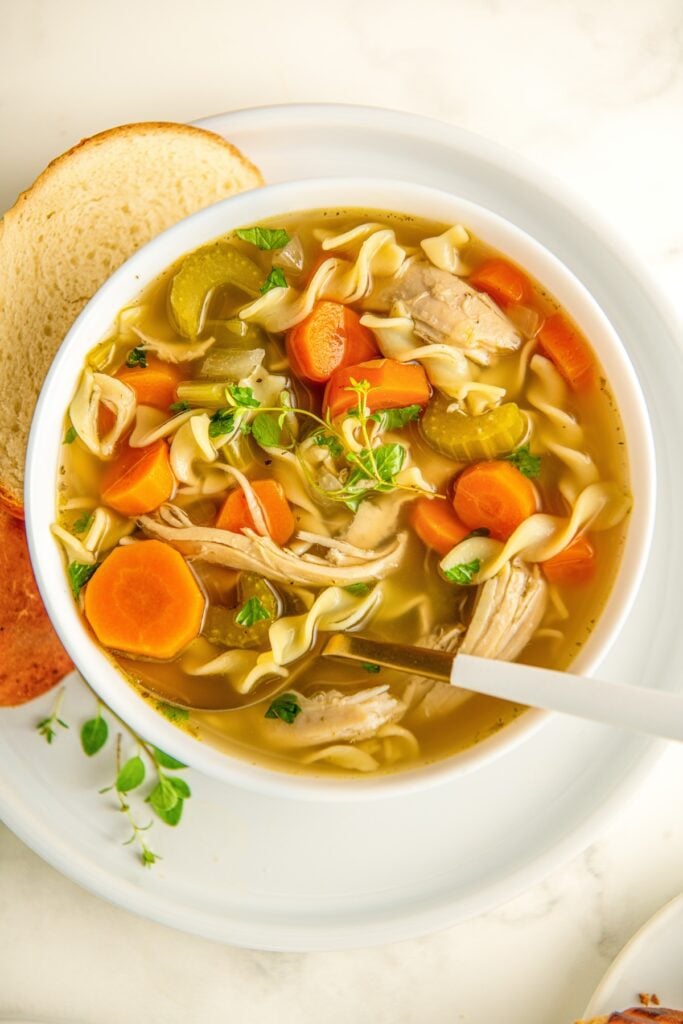 Crockpot chicken noodle soup with egg noodles in a bowl with a spoon lifting a bite.