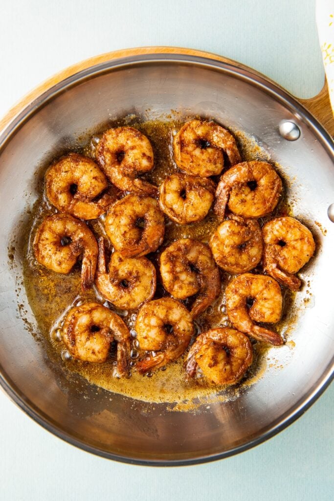 Seasoned shrimp cooking in a skillet.