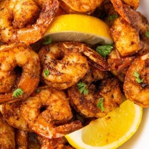 Blackened shrimp garnished with lemons and fresh herbs.