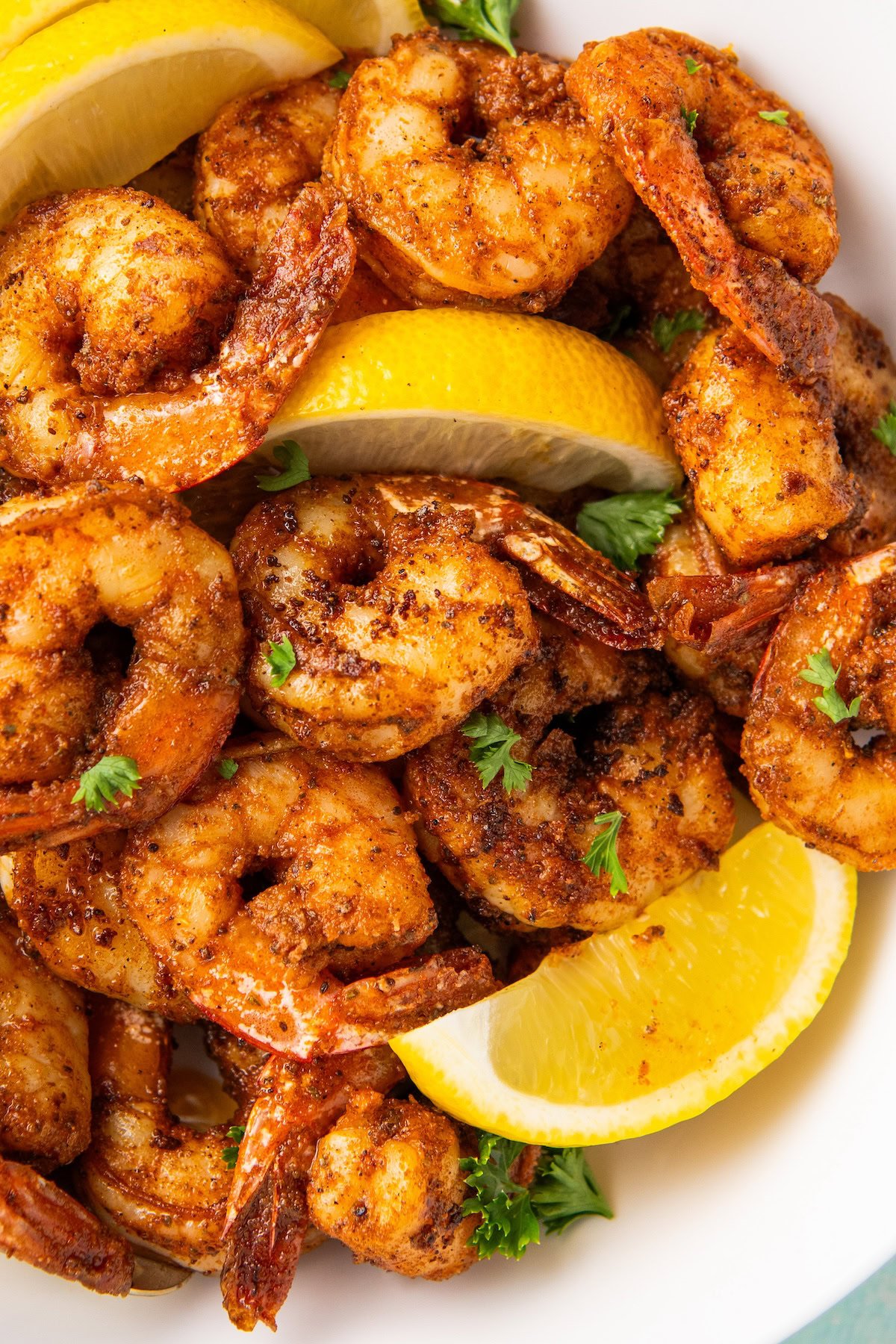 Juicy and tender blackened shrimp garnished with lemons and fresh herbs.