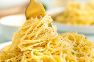 Parmesan pasta is being twirled by a fork.