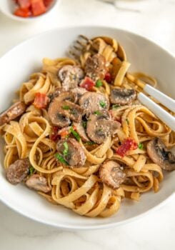 Creamy mushroom pasta with bacon, fresh parsley and grated parmesan cheese sprinkled on top in a bowl.