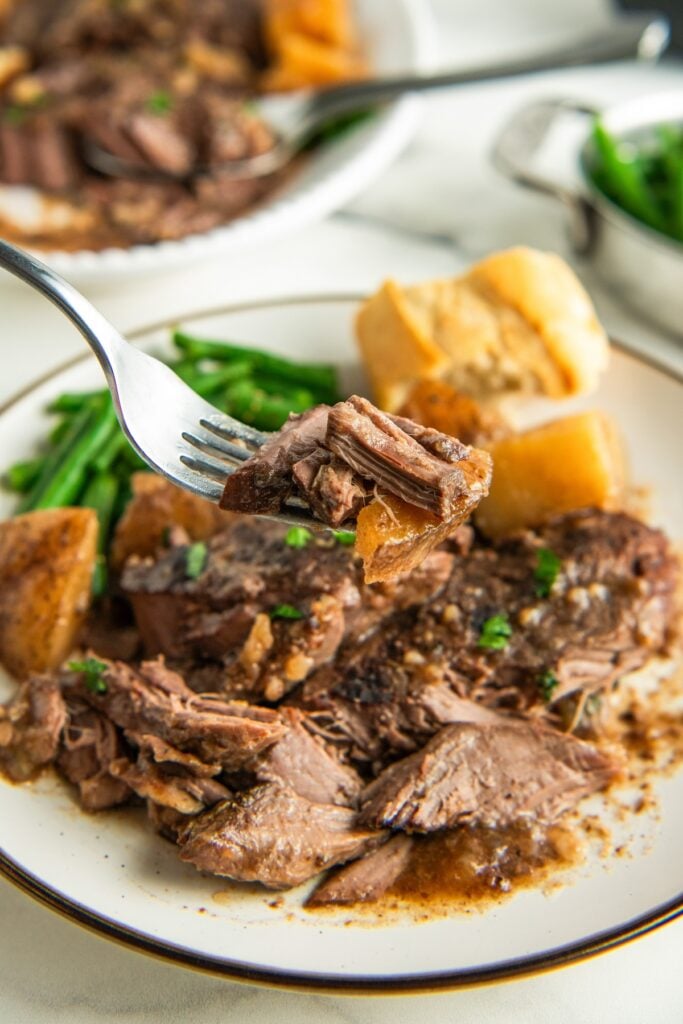 A bite of steak is lifted from a plate.