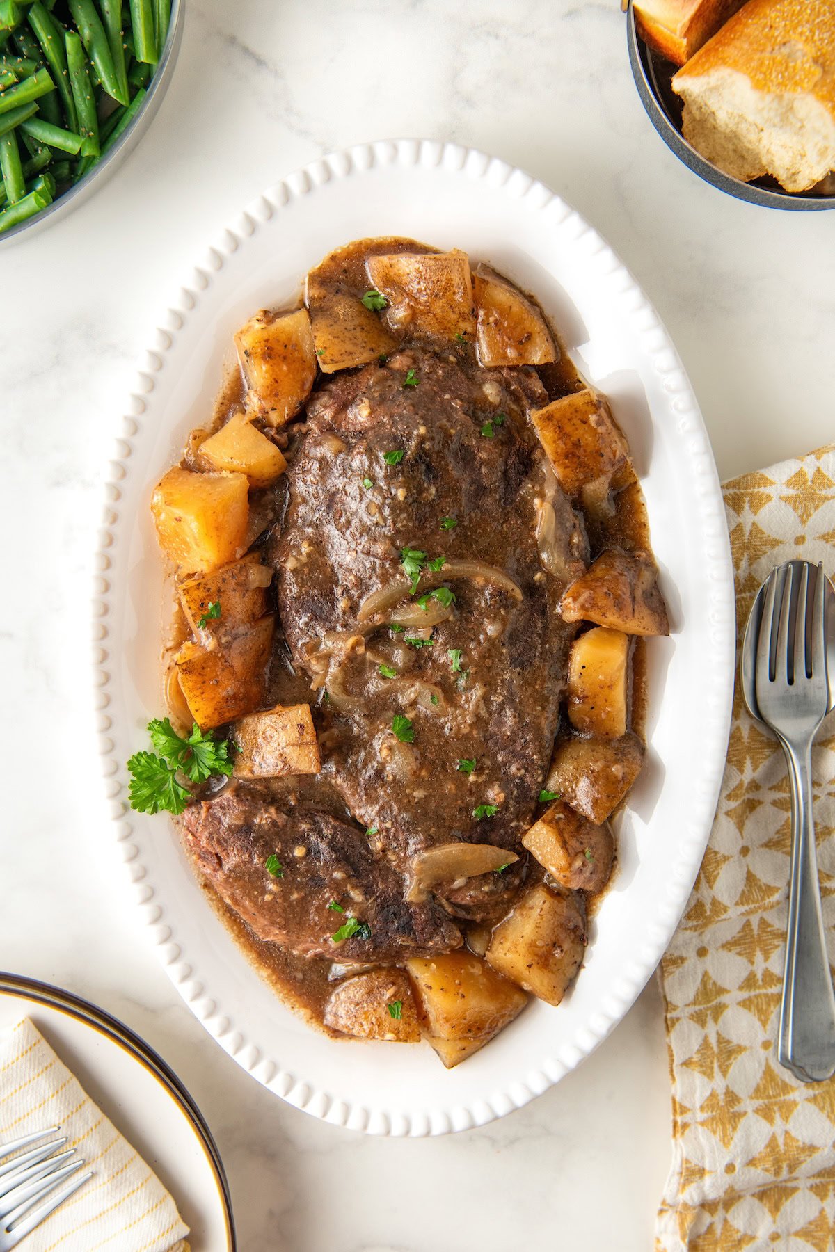 Crockpot steak and potatoes are presented on a white platter.