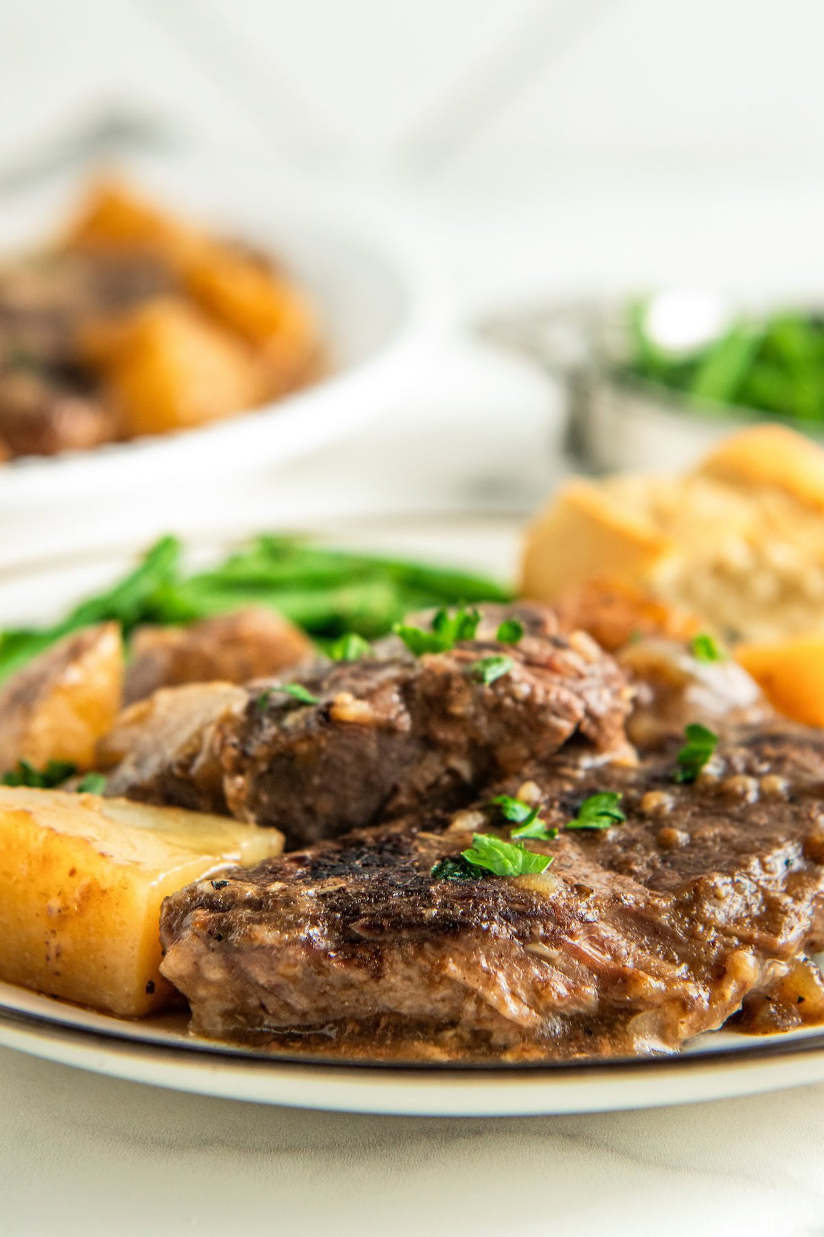 Slow cooker steak and potatoes are on a plate, garnished with fresh parsley.