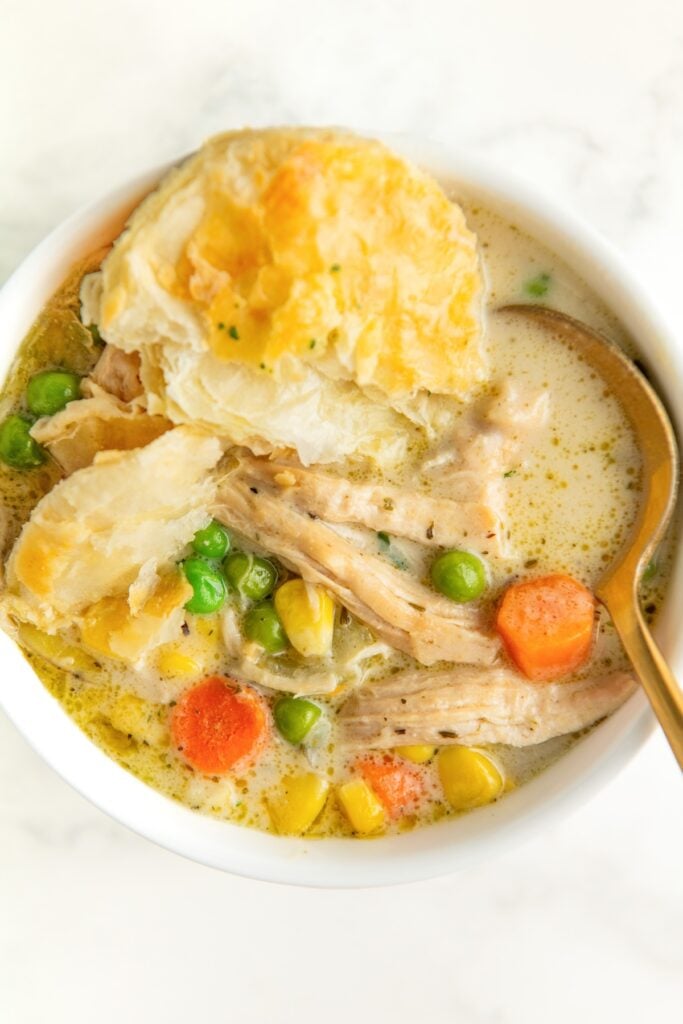 A spoon is placed in a bowl filled with creamy chicken pot pie soup.