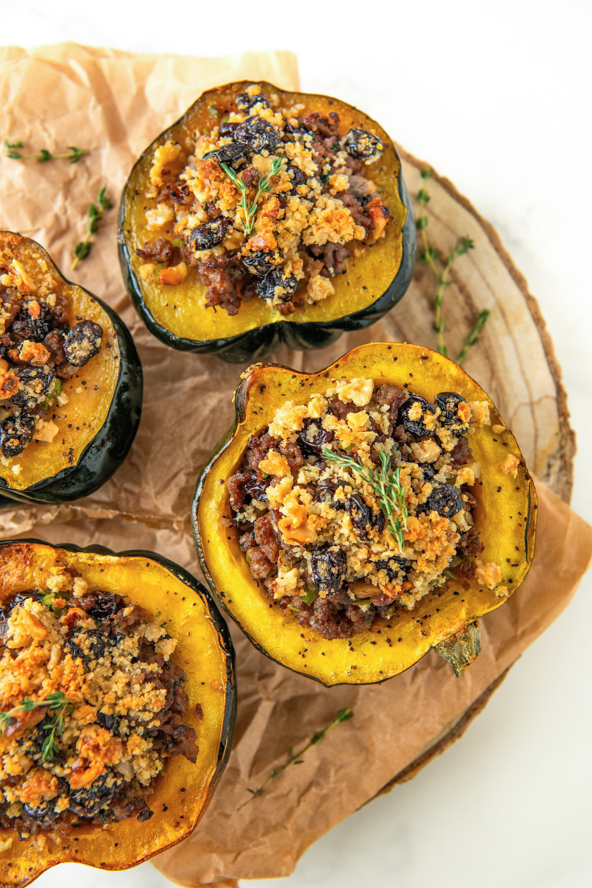 Several servings of sausage stuffed acorn squash on a round serving platter topped with fresh herbs.