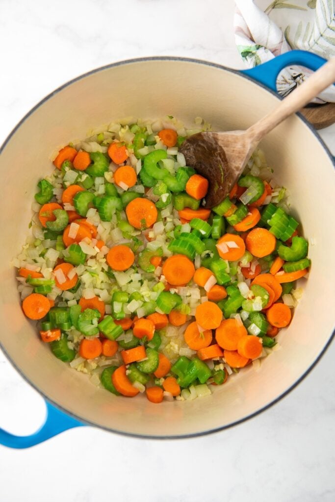 Vegetables are sautéing in a large dutch oven.