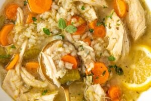 A white bowl is filled with a single serving of chicken lemon rice soup.