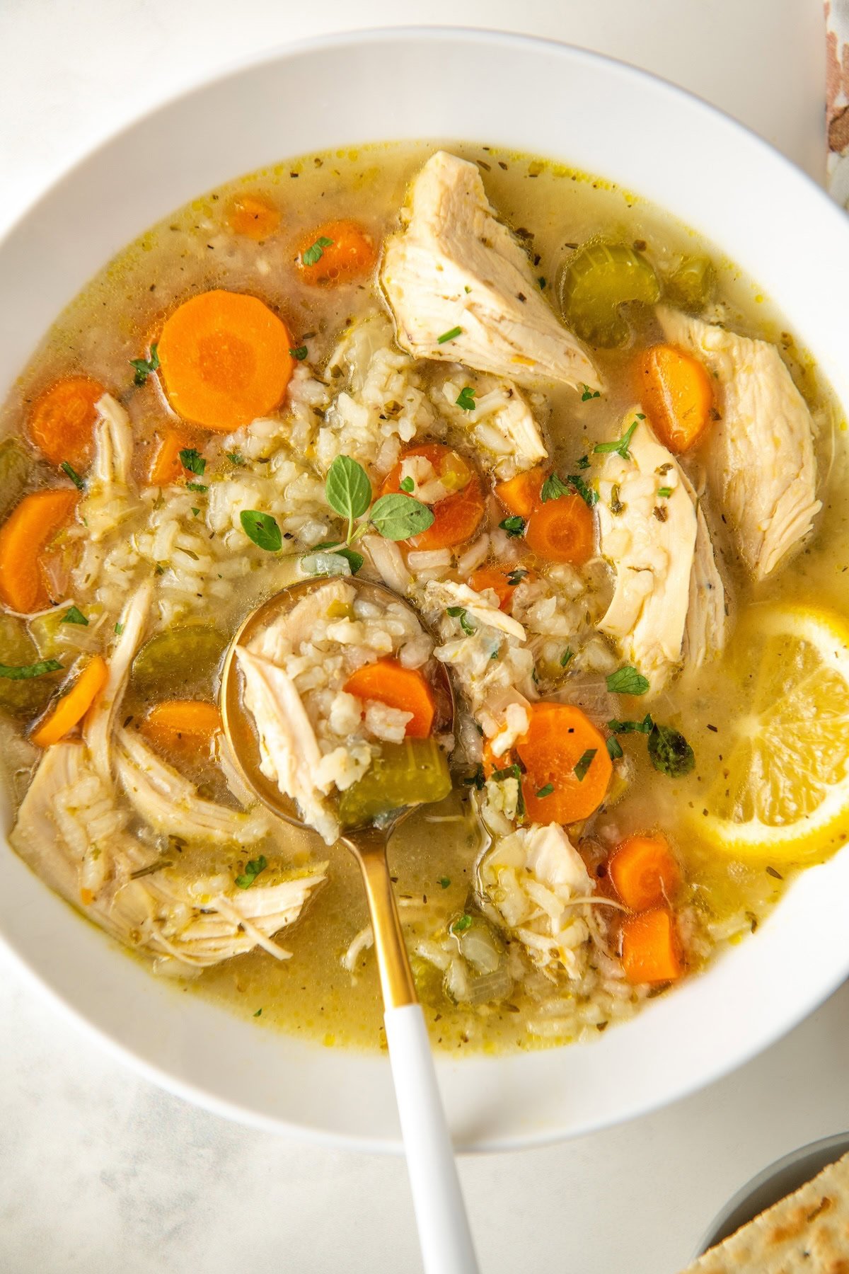 A white bowl is filled with a single serving of chicken lemon rice soup.