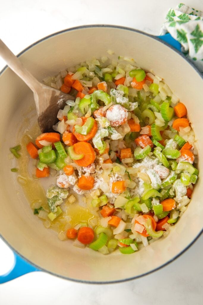 Vegetables are being sautéed in a large dutch oven.