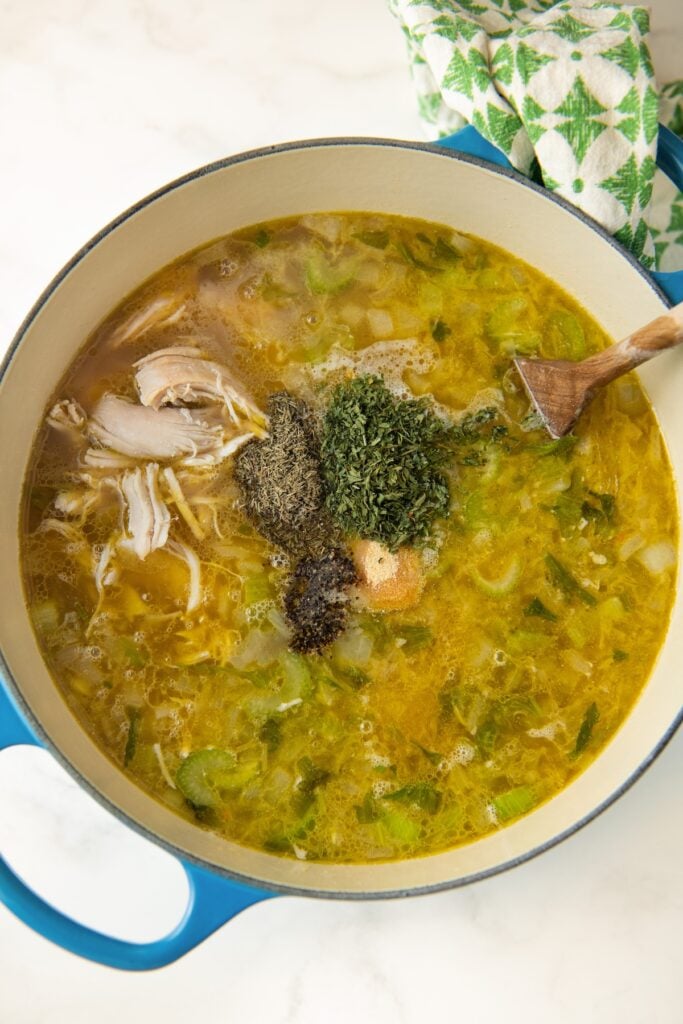 Herbs and broth are mixed into the pot.