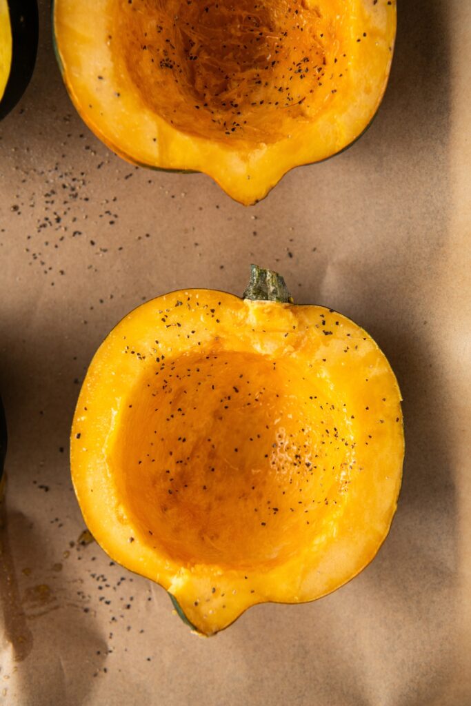 Sliced acorn squash halves placed on a baking sheet.