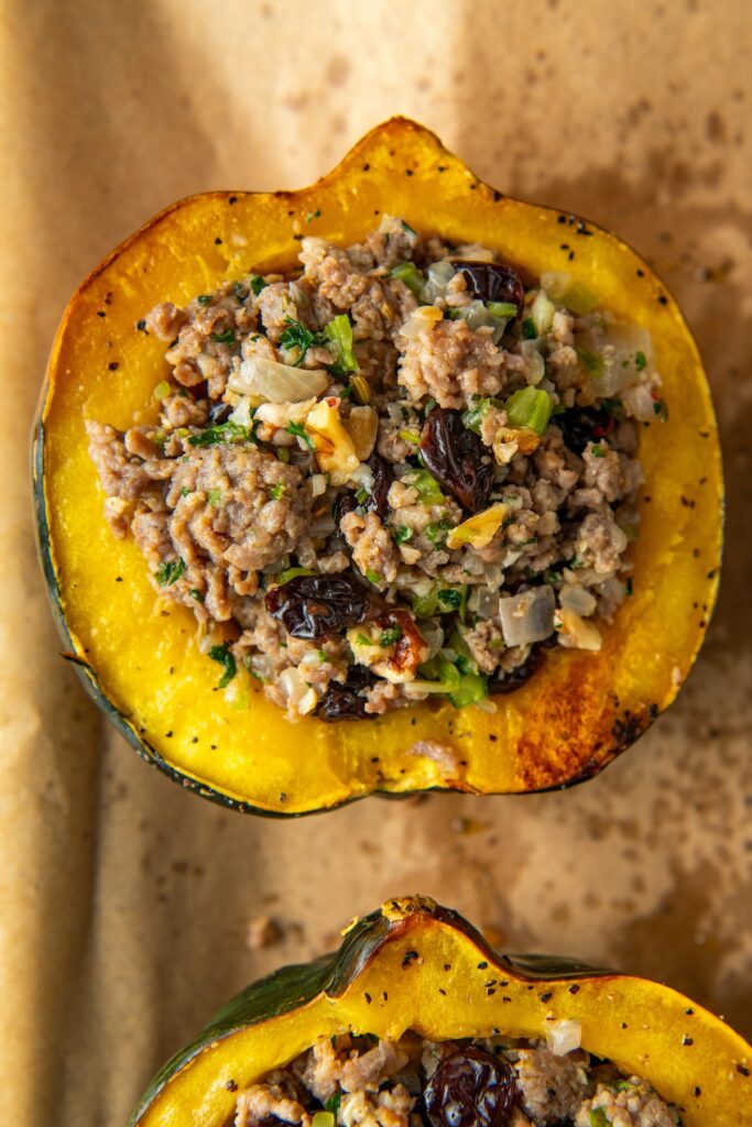 Acorn squash stuffed with sausage on a baking sheet.