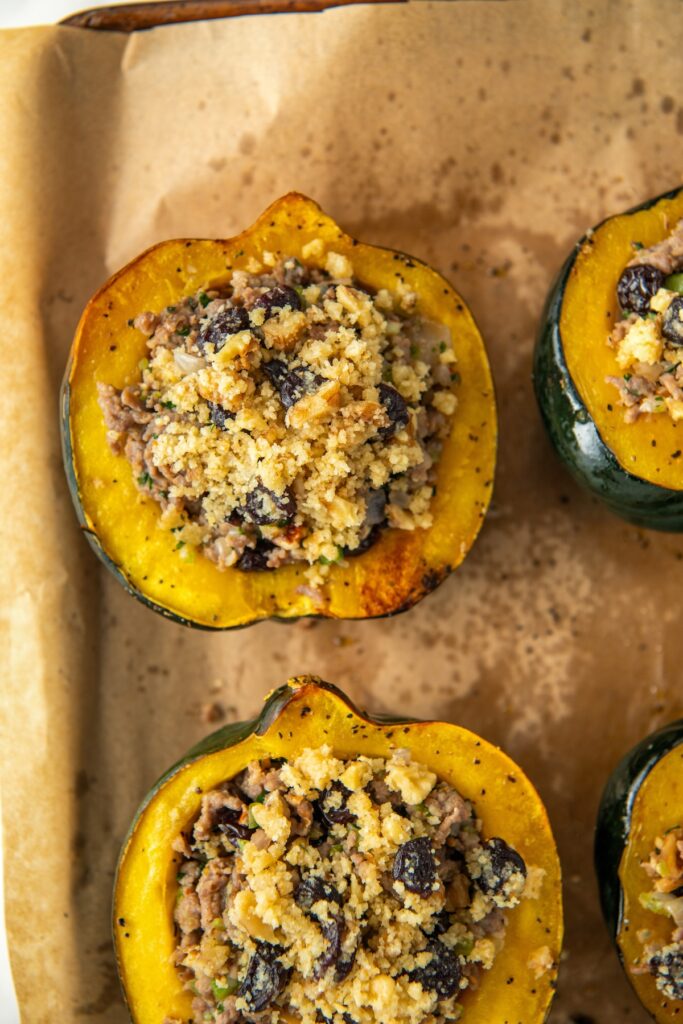 Several servings of sausage stuffed acorn squash are presented on a baking sheet.