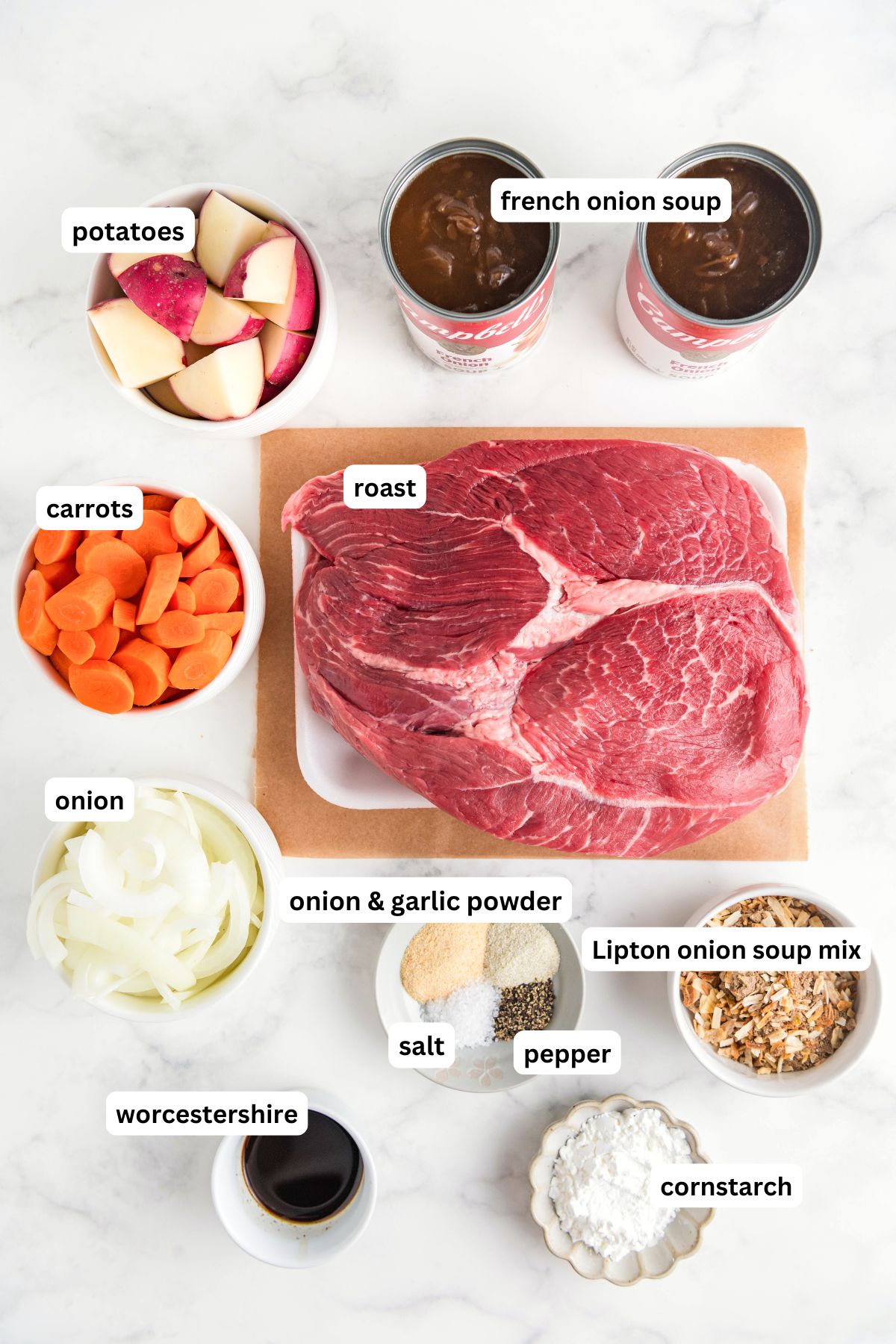 The ingredients for slow cooker French onion pot roast recipe in order from top to bottom: potatoes, French onion soup, carrots, roast, onion, onion and garlic powder, salt, pepper, Lipton onion soup mix, Worcestershire, cornstarch.