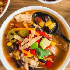 A spoon is placed in a bowl of chicken tortilla soup.