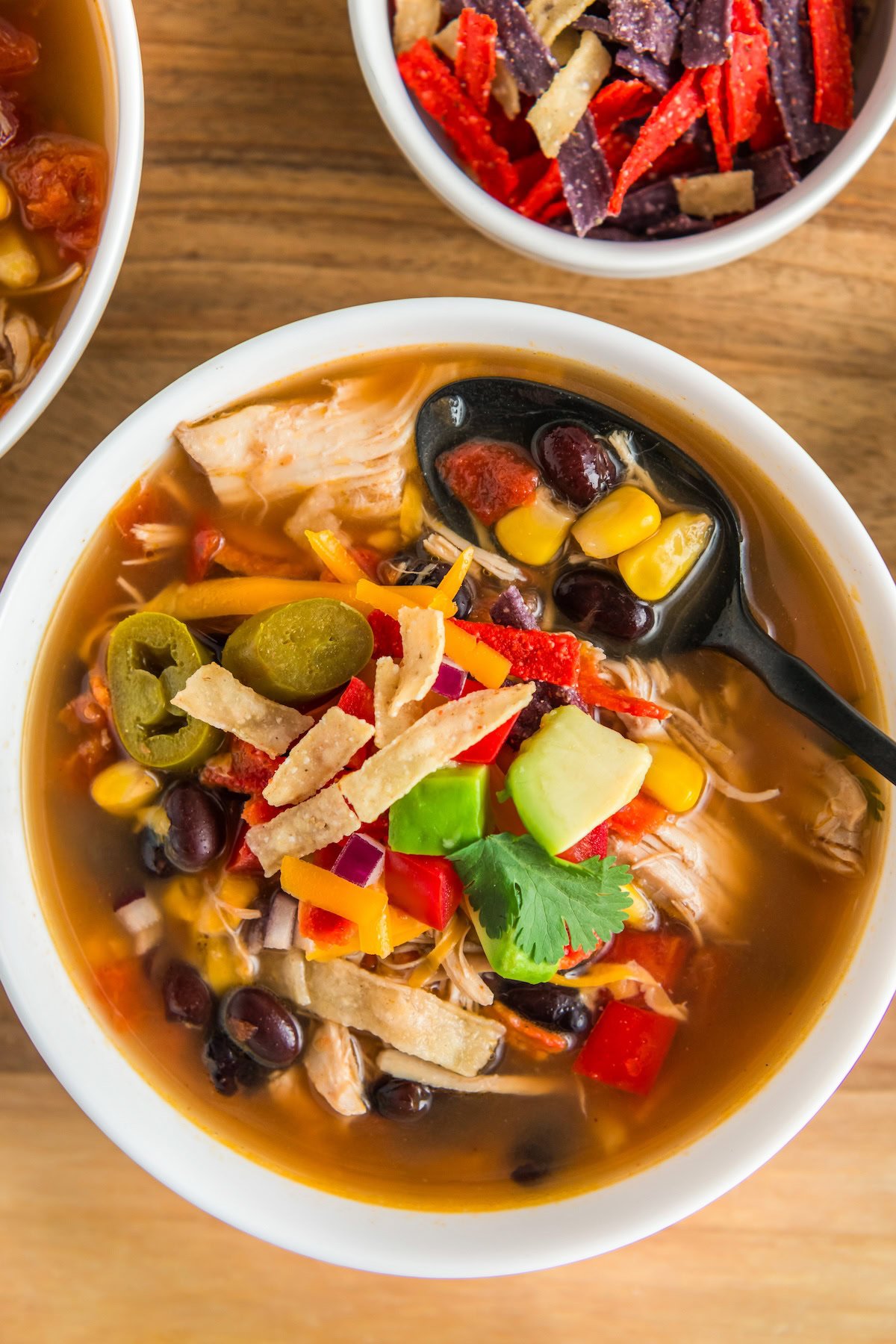 A spoon is placed in a bowl of chicken tortilla soup.