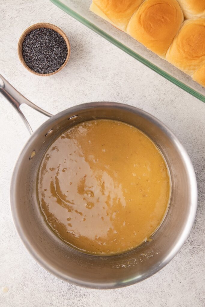 A buttery mustard sauce is cooking in a small sauce pot.