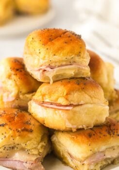 A small stack of Hawaiian ham and cheese sliders presented on a white plate.