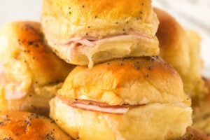 A small stack of Hawaiian ham and cheese sliders presented on a white plate.