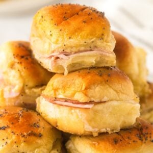 A small stack of Hawaiian ham and cheese sliders presented on a white plate.