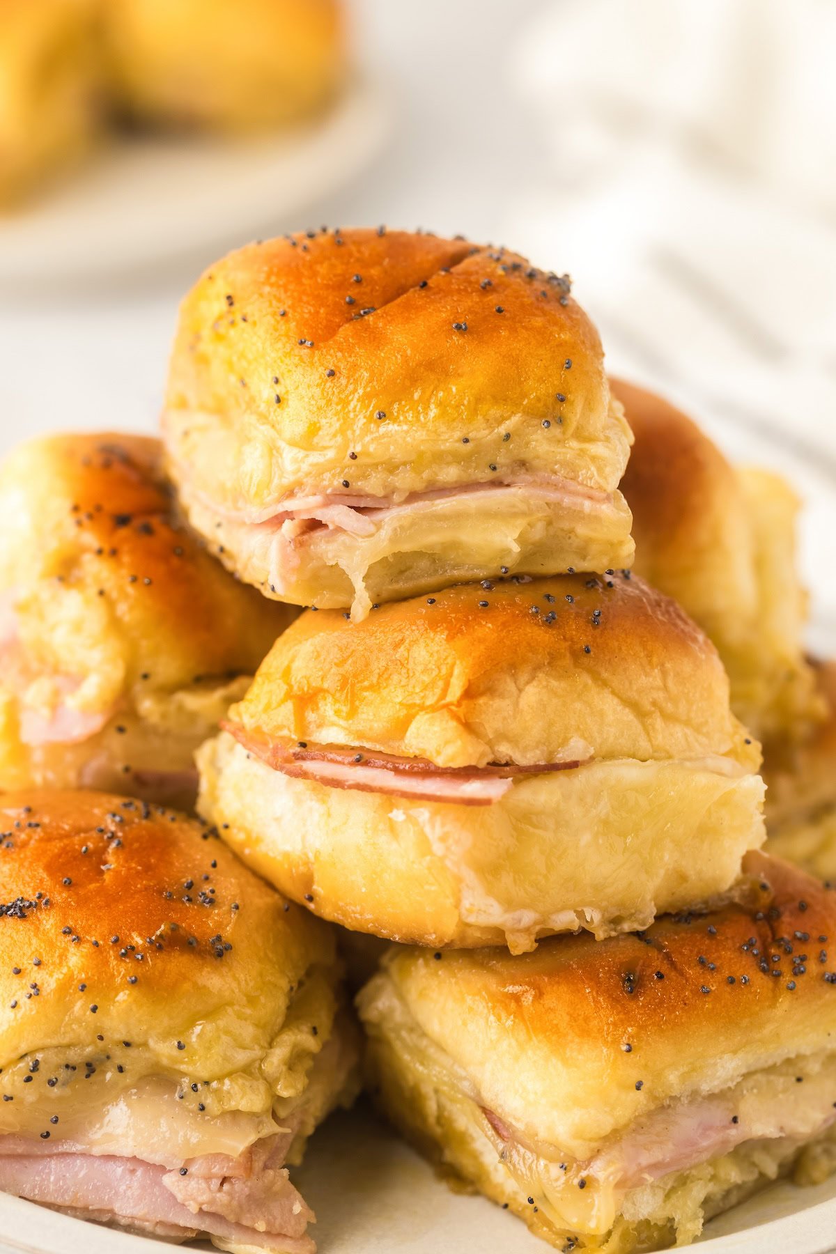 A small stack of Hawaiian ham and cheese sliders presented on a white plate.