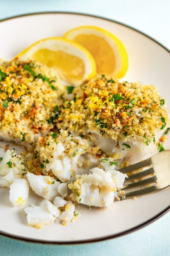 Flaky white fish is being picked apart with a fork.