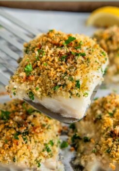 A serving of parmesan crusted cod is being lifted from a sheet pan.