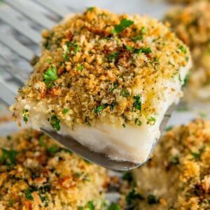 A serving of parmesan crusted cod is being lifted from a sheet pan.